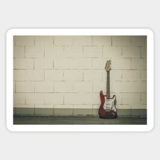 Red electric guitar against white brick wall Sticker